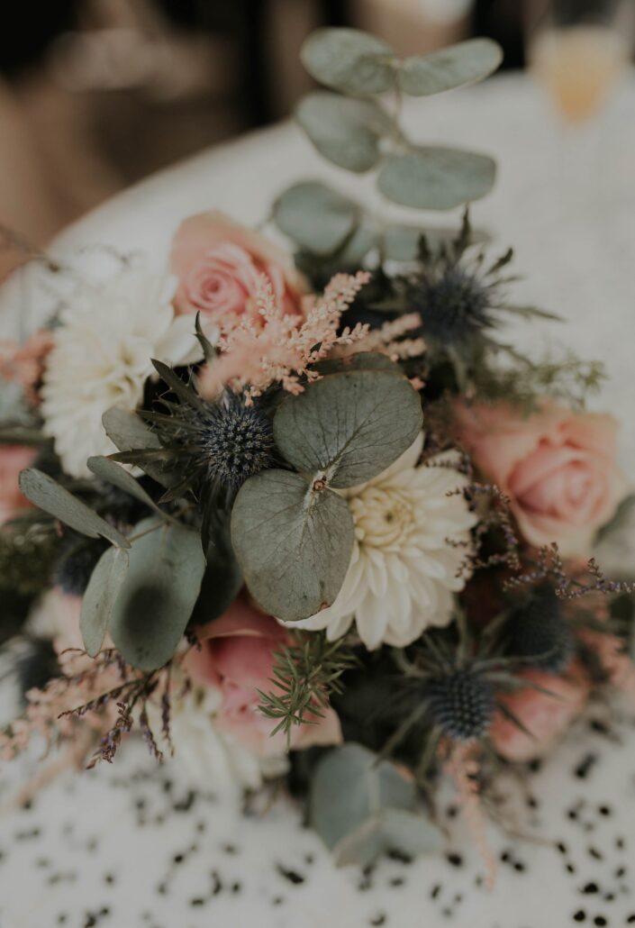 brautstrauss-mit-disteln-liegt-auf-einem-tisch-hochzeitsfotograf-muenster-madameklick